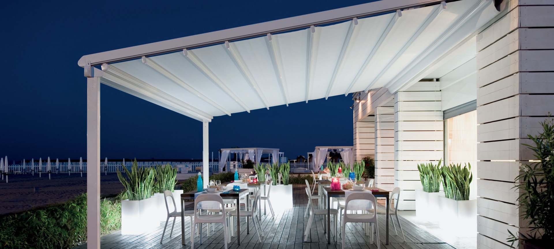 Gece aydınlatmalı otomatik tente ile deniz kenarı restoran terası